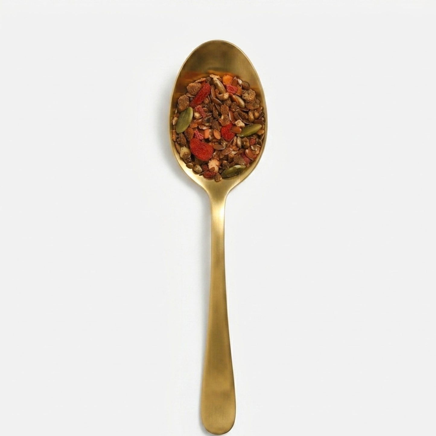 Gold spoon filled with a mixture of seeds and dried fruit on a white background