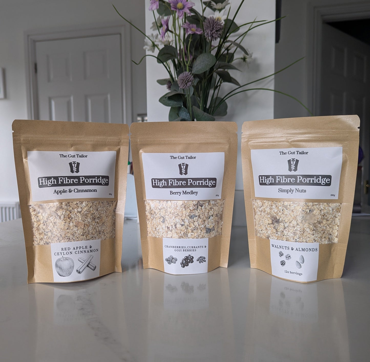 Three packages of High Fiber Porridge on a kitchen counter with a vase of flowers in the background.