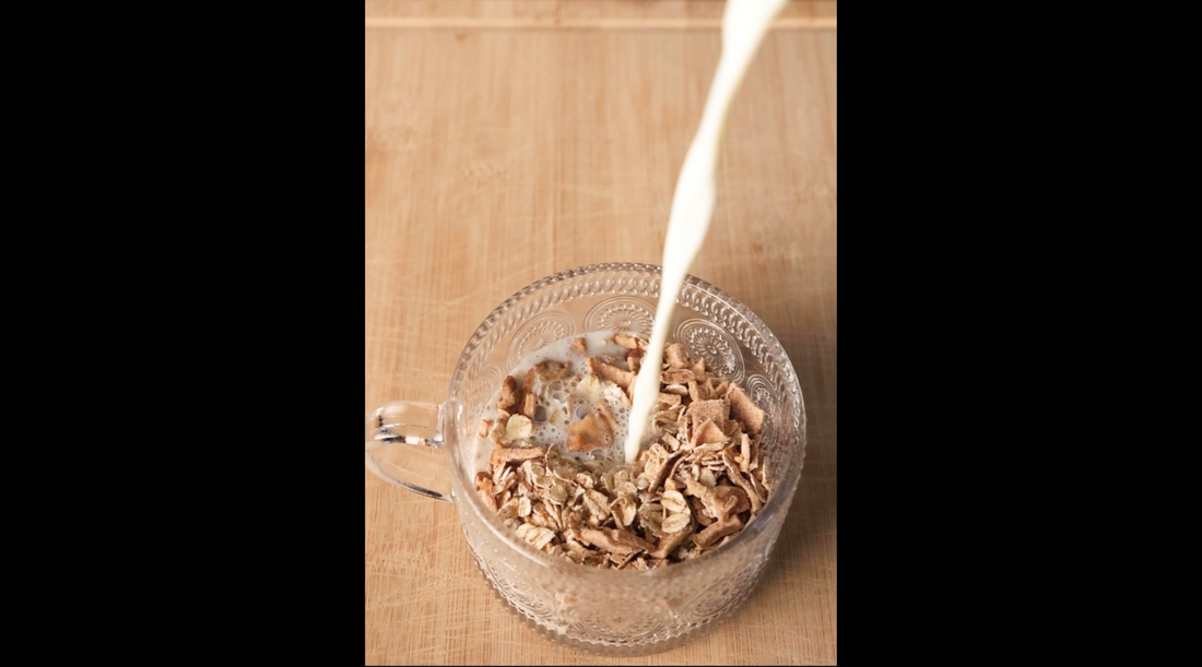 Milk pouring into a bowl of overnight oats on a wooden table