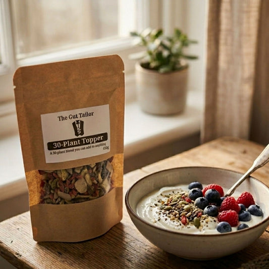 Bag of 'The Gut Tailor' 30-Plant Topper next to a bowl of yogurt with berries on a wooden surface.