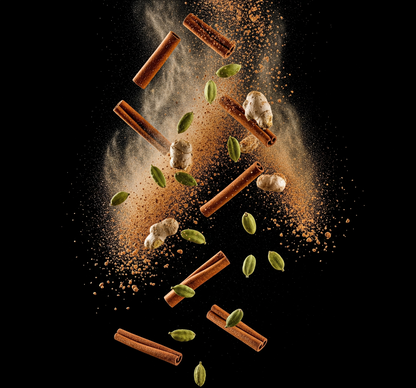 Cinnamon sticks, ginger powder and cardamom pods falling against a black background