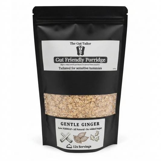 A black stand-up pouch of 'The Gut Tailor' Gut Friendly Porridge, Gentle Ginger flavor, with a clear window showing the beige oatmeal inside. The packaging features white labels with black text and illustrations.