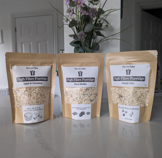 Three packages of High Fiber Porridge on a kitchen counter with a vase of flowers in the background.